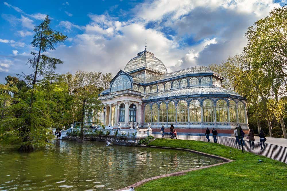 Palais de cristal devant un plan d'eau et entouré d'arbres