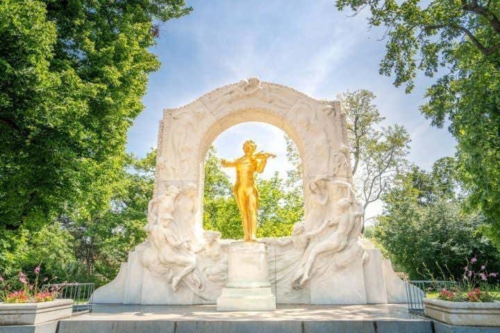 Statue dorée entourée d'un monument blanc au sein d'un parc