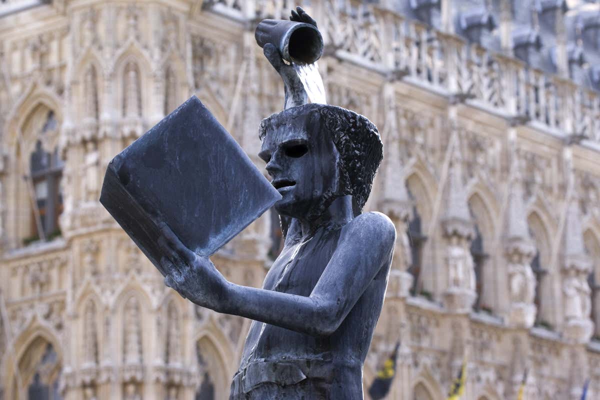 Fontaine Fonske, “Source de Sagesse”, à Louvain : statue d'un jeune homme tenant un livre ouvert et se versant un verre d'eau sur la tête