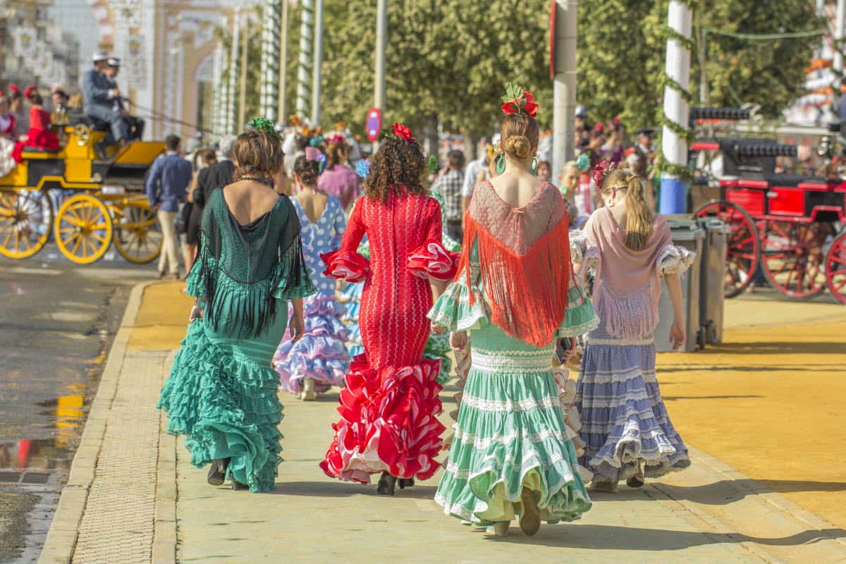 Mujeres andando con trajes de flamenco en un día soleado