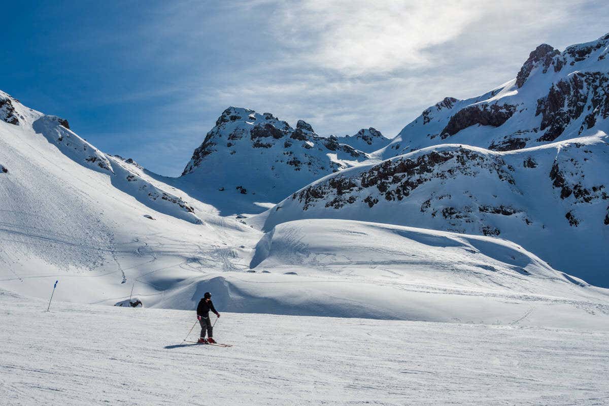 Persona con casco e indumenti invernali scia sui Pirenei Aragonesi innevati in un giorno di sole.