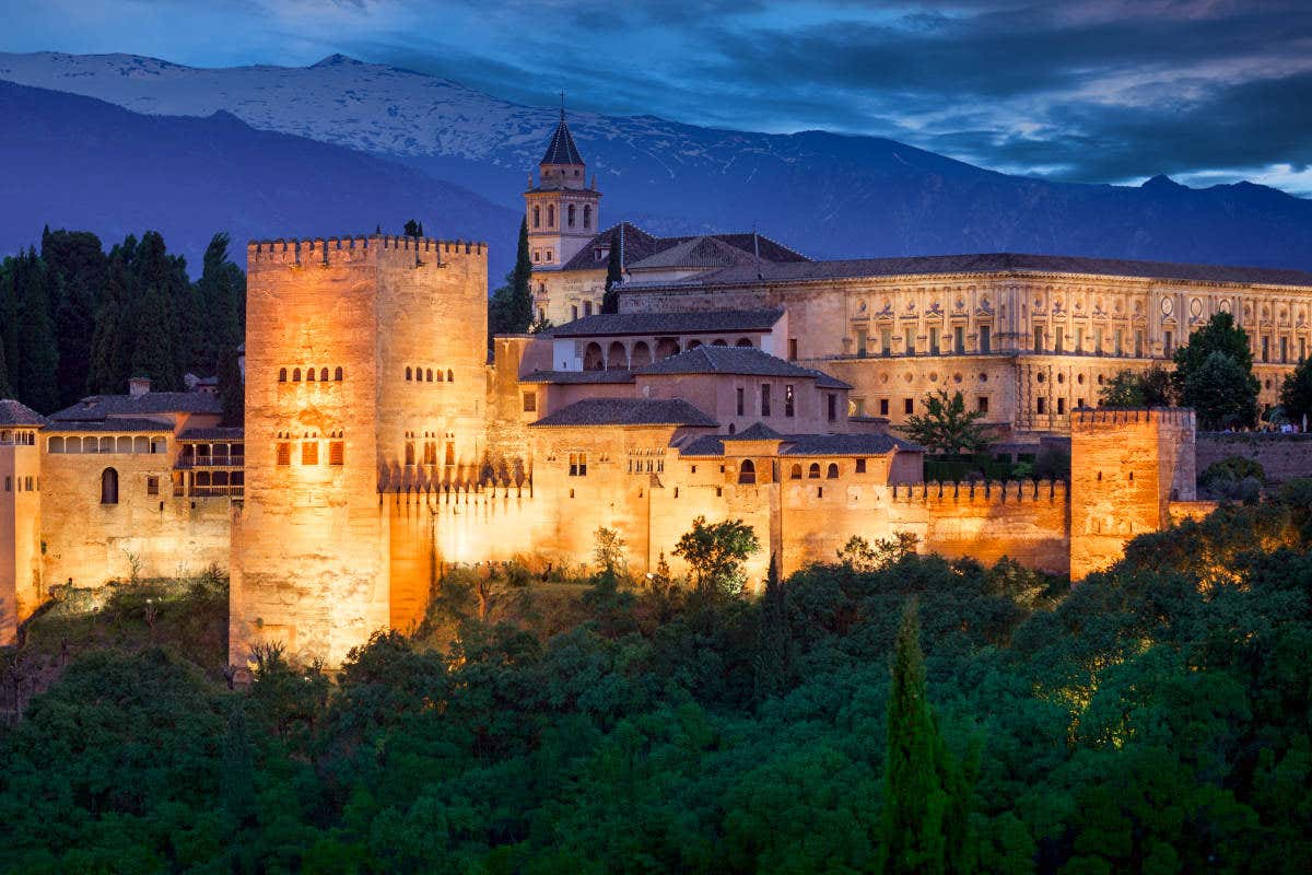 L'Alhambra di Granada, il complesso monumentale Patrimonio dell'Umanità, illuminata  di sera e circondata dalla lussureggiante vegetazione.