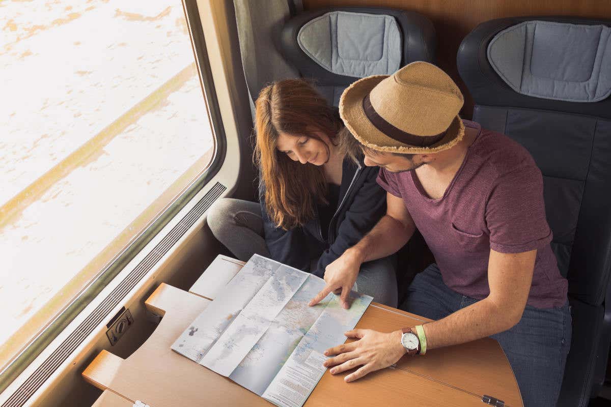 Un couple dans un train regardant une carte, préparant un itinéraire