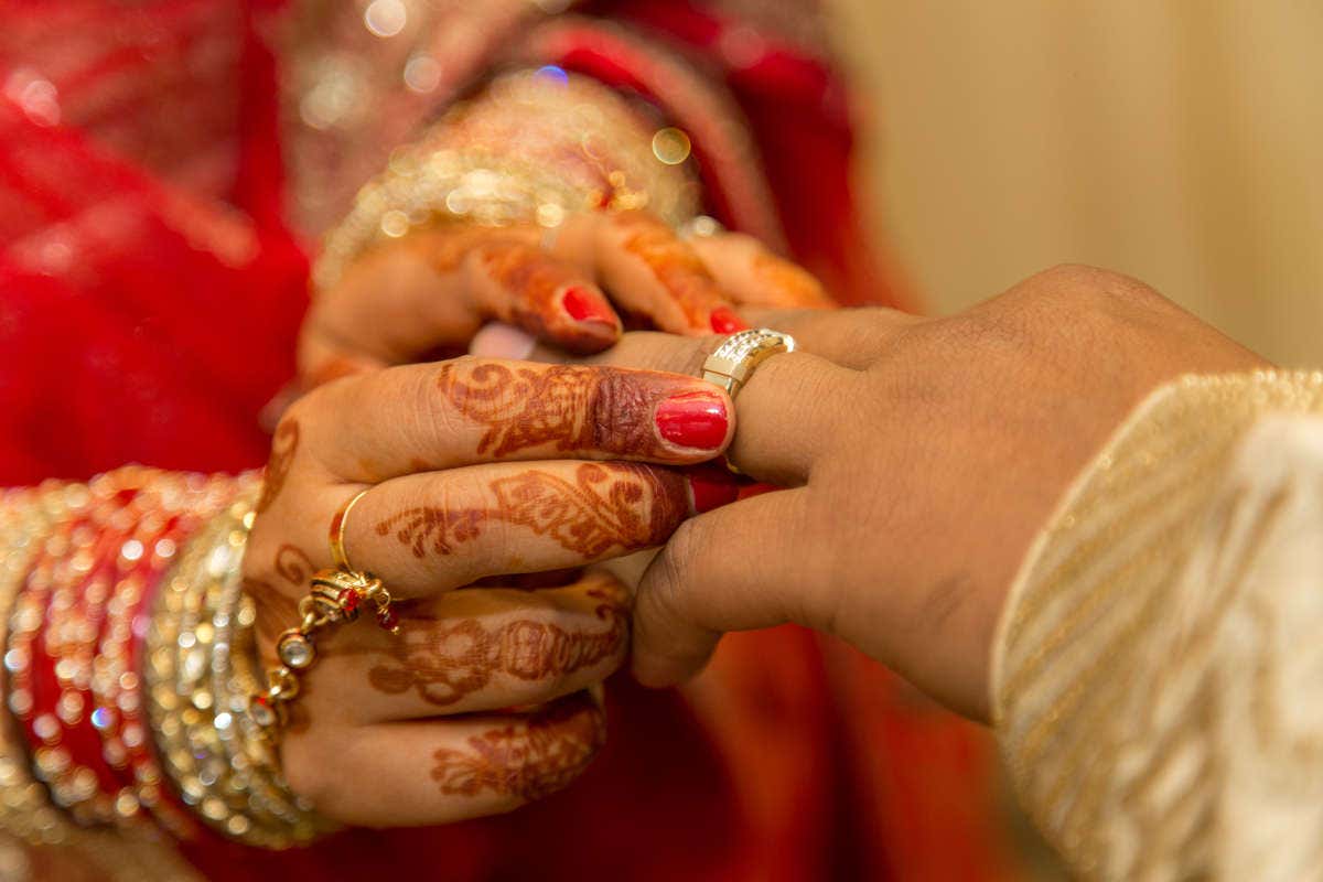 Una mujer le coloca la alianza a su marido en una boda tradicional hindú
