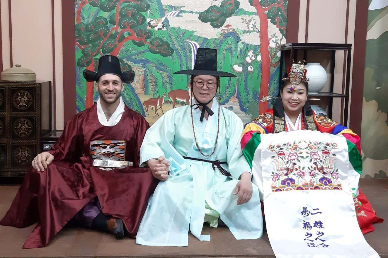 Un monje coreano sostiene la mano de una pareja vestida con los trajes tradicionales nupciales de Corea