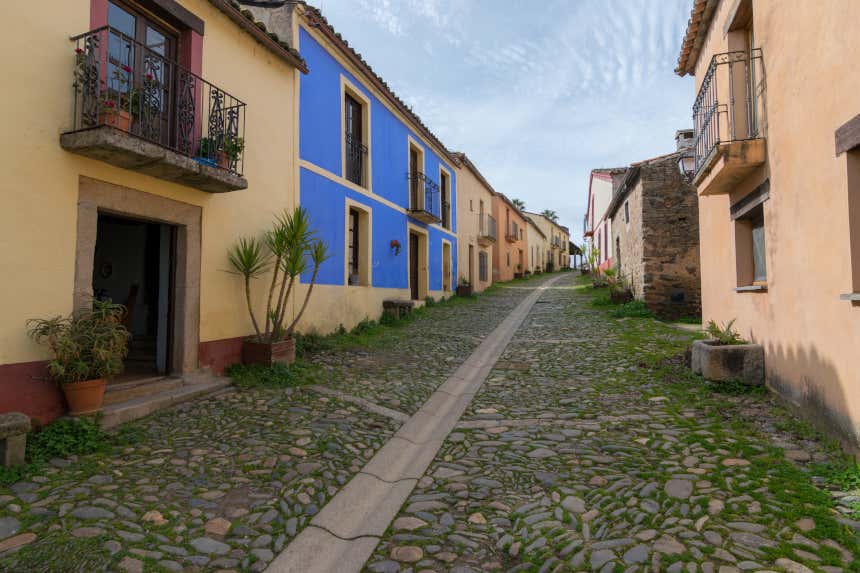 Una calle adoquinada con fachadas de colores del pueblo abandonado de Granadilla, en Cáceres