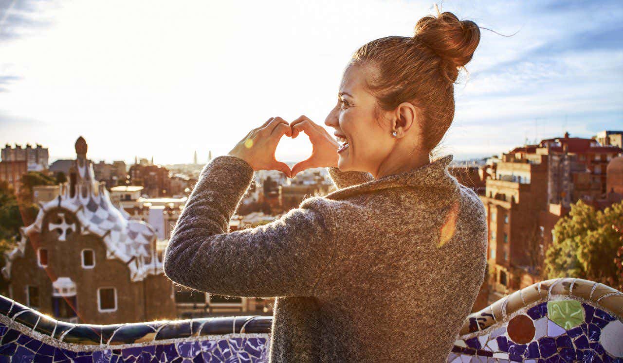 Mujer dibujando un corazón con las manos en el Parque Güell