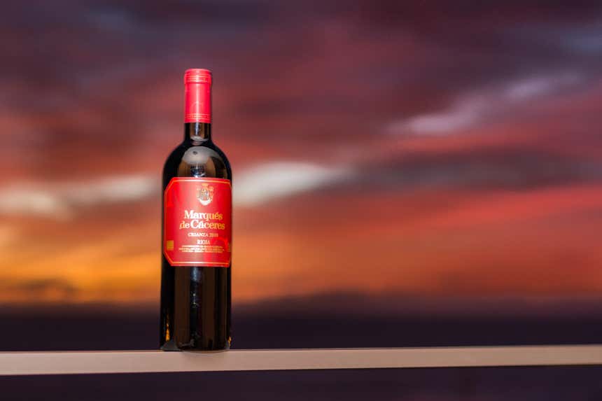 Botella de vino de las bodegas Marqués de Cáceres sobre un cielo atardeciendo.