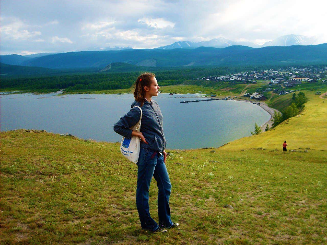 Anna Bondareva en primer plano con el lago Baikal y las montañas nevadas del sur de Siberia al fondo.