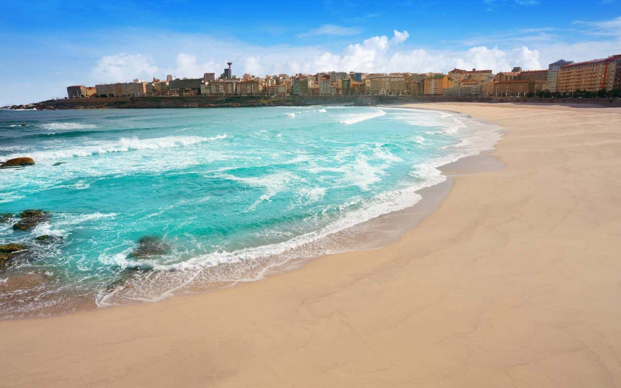 A Praia de Riazor se destaca por sua forma de concha e está perto da cidade