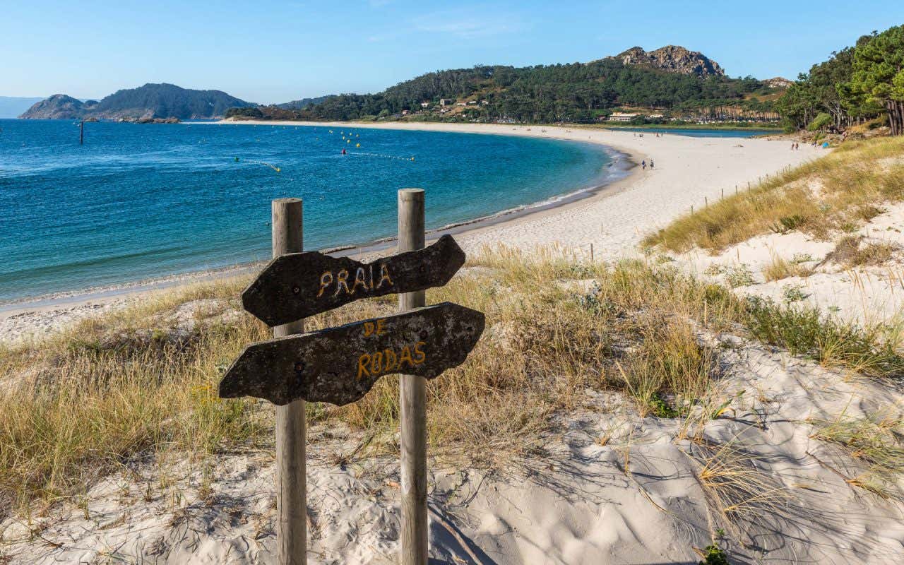 Placas na areia indicando a Praia Rodas, com o mar ao fundo