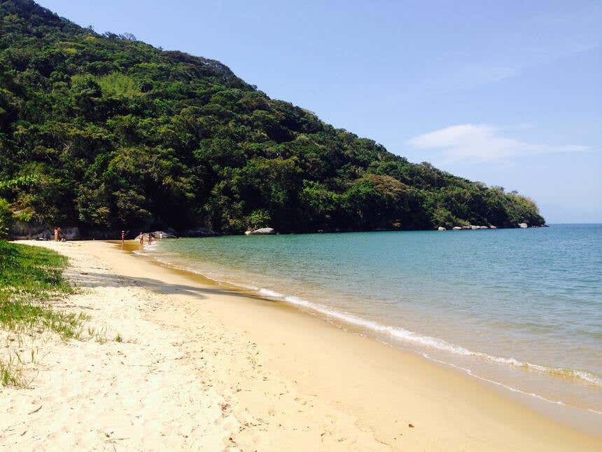 Praia tranquila com uma montanha coberta de vegetação ao fundo