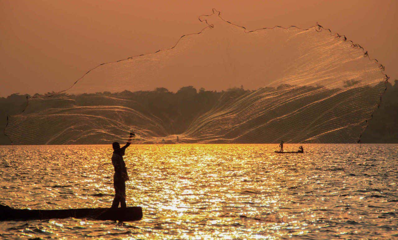 Pescador soltando las redes en el lago Victoria al atardecer