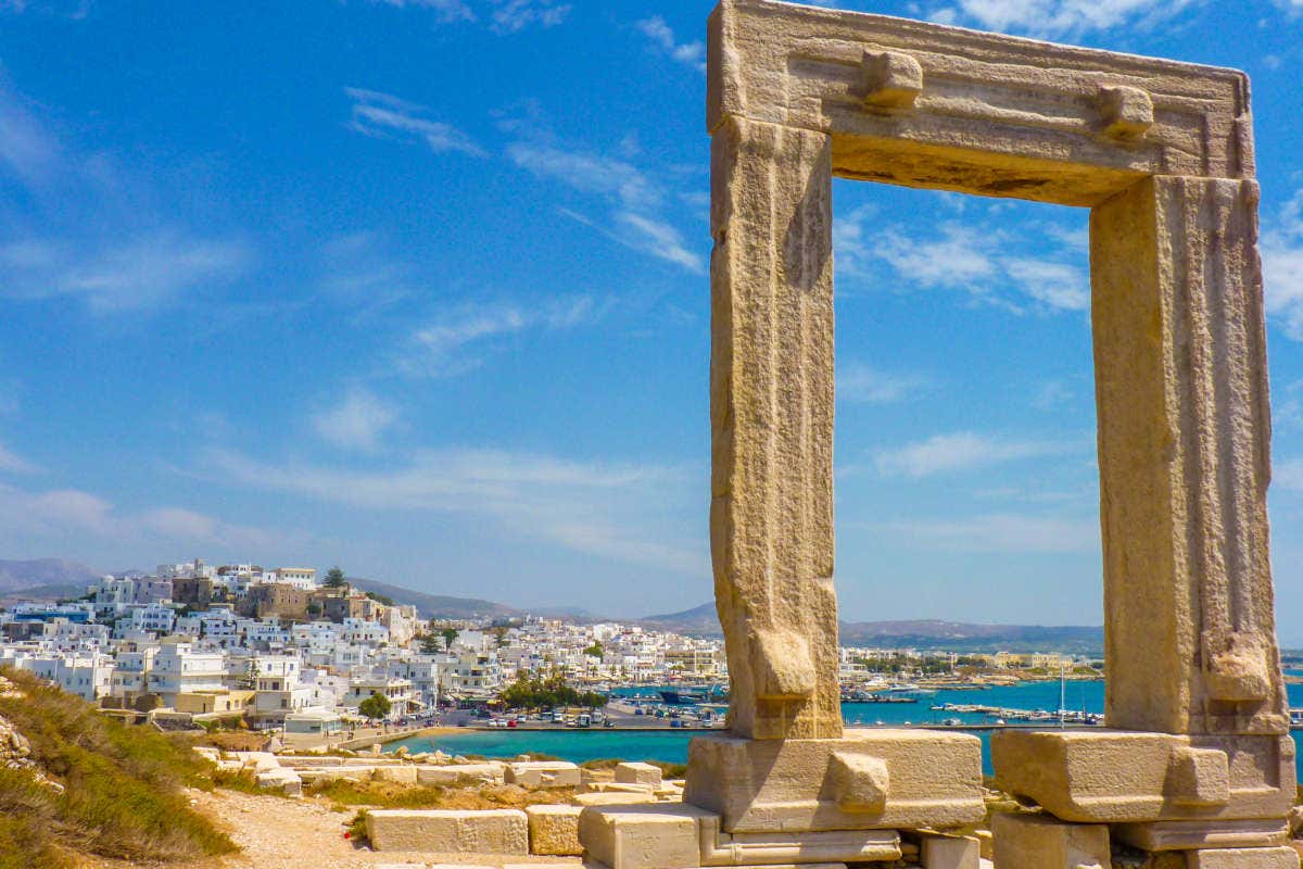 Restos arqueológicos de Portara y la ciudad de Naxos al fondo en un día soleado en Grecia