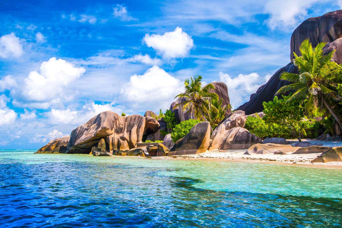 La bellissima spiaggia tropicale Source d’Argent nelle Seychelles, con imponenti formazioni rocciose e palme