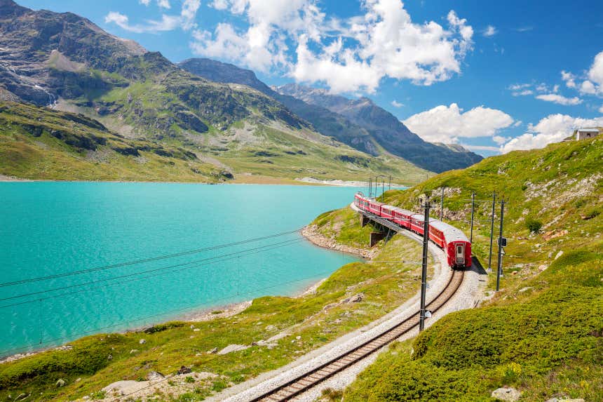 Bernina Express atravessando os Alpes com as paisagens verdes e dos lagos ao fundo.