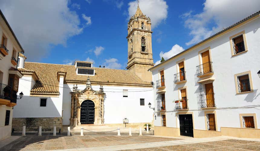 Una iglesia de Cabra, de fachada blanca y con una torre de piedra con varias campanas