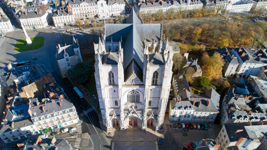 Vista aérea de la Catedral de San Pedro y San Pablo en Nantes con planta de cruz latina y rodeada por arboles y edificios residenciales