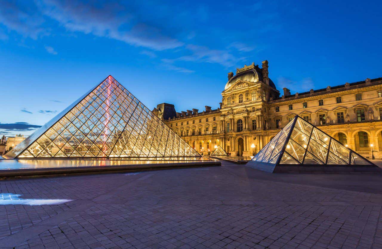 Famosa entrada del Museo del Louvre con las pirámides de cristal en la noche de París