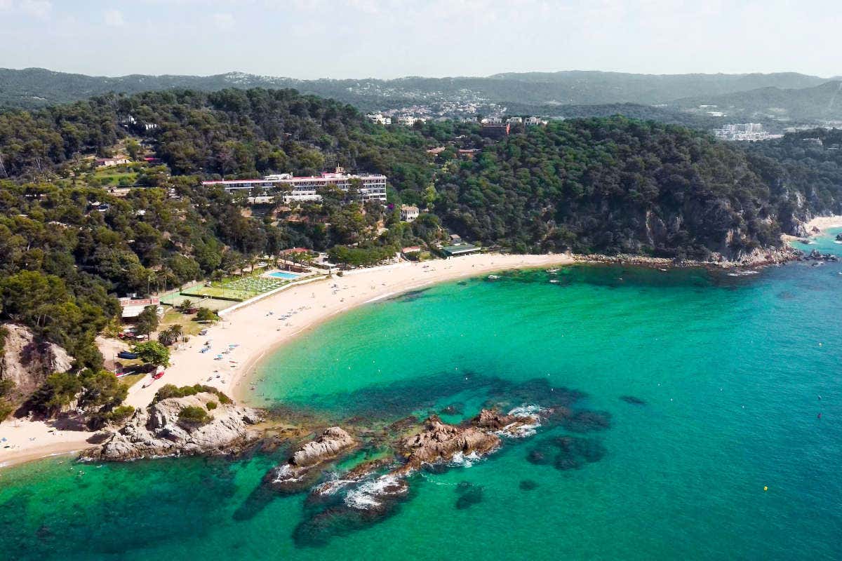 View looking onto the beachfront with fine white sand and crystalline turquoise water surrounded by dense trees