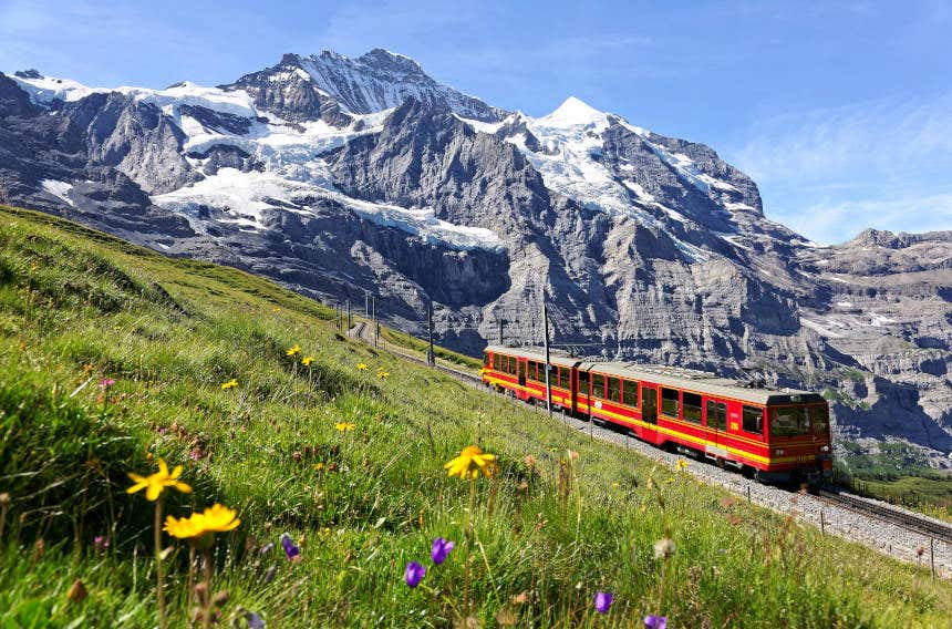 Trem cremalheira atravessando os Alpes com as montanhas nevadas ao fundo