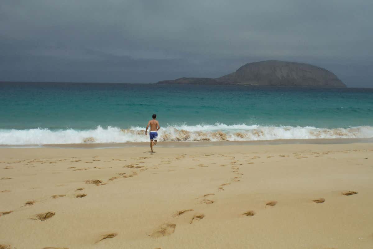 Aguas turquesas, arena dorada y David Chaves corriendo hacia el agua en la isla de La Graciosa.