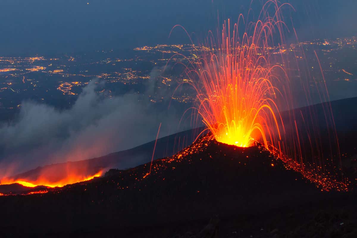 Vue nocturne de l'Etna en éruption et crachant de la lave près de Catane