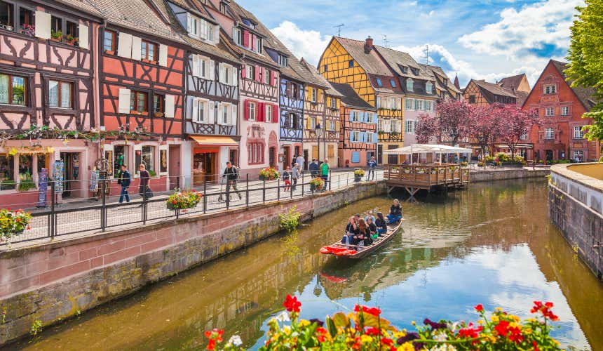 Un grupo de turistas disfrutando de un paseo en barco por uno de los canales de la Pequeña Venecia de Colmar, un plan imprescindible que hacer en Alsacia