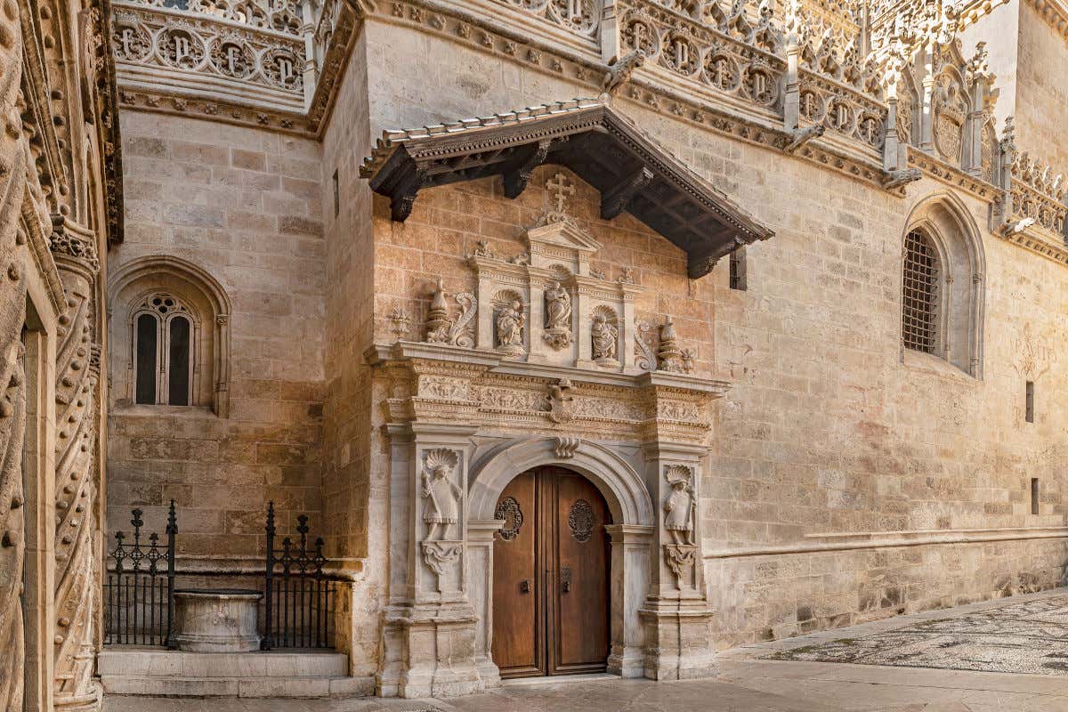 Vista exterior del pórtico de piedra de la Capilla Real de la catedral de Granada. Se pueden ver varias esculturas y, arriba de la imagen, símbolos de los Reyes Católicos, Isabel de Castilla y Fernando de Aragón.