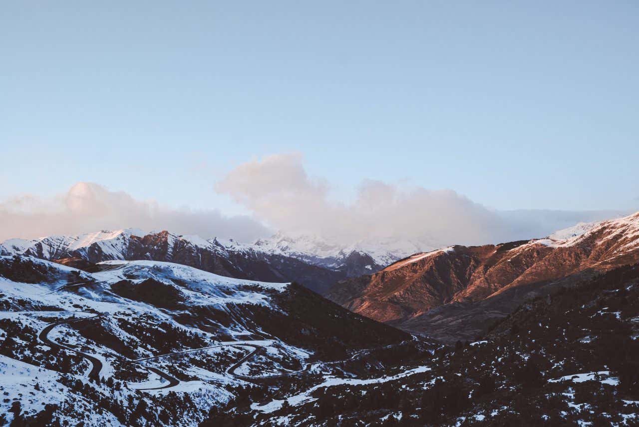 Paysages de montagnes partiellement enneigées sous un ciel bleu, un endroit où skier en Espagne