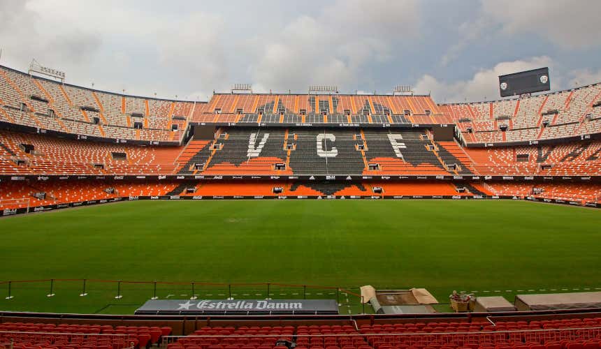 Panorámica de las gradas rojizas del estadio de Mestalla con el campo de juego de un color verde intenso