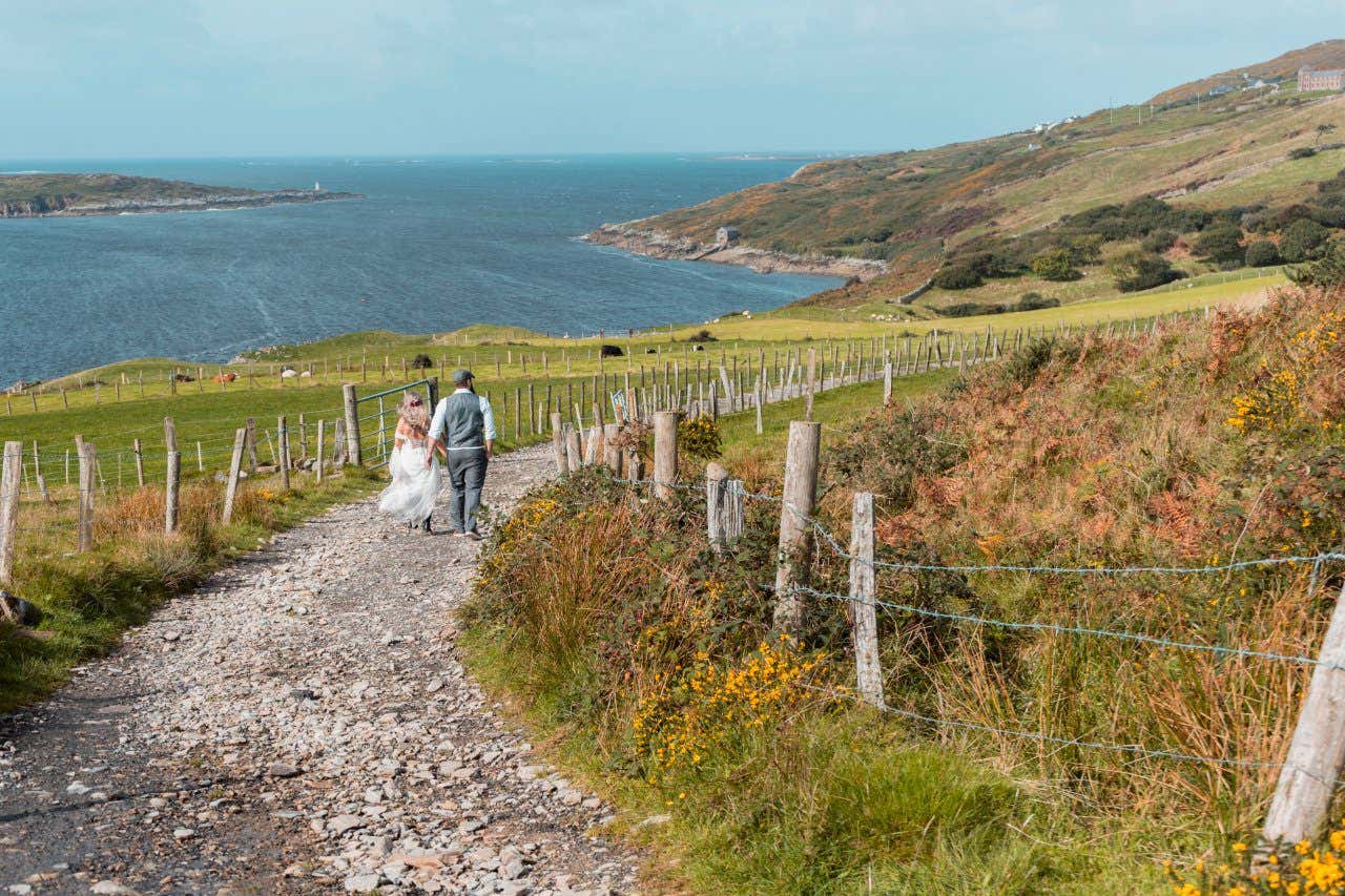 A man and a woman walking down a stone path on the Irish coastline