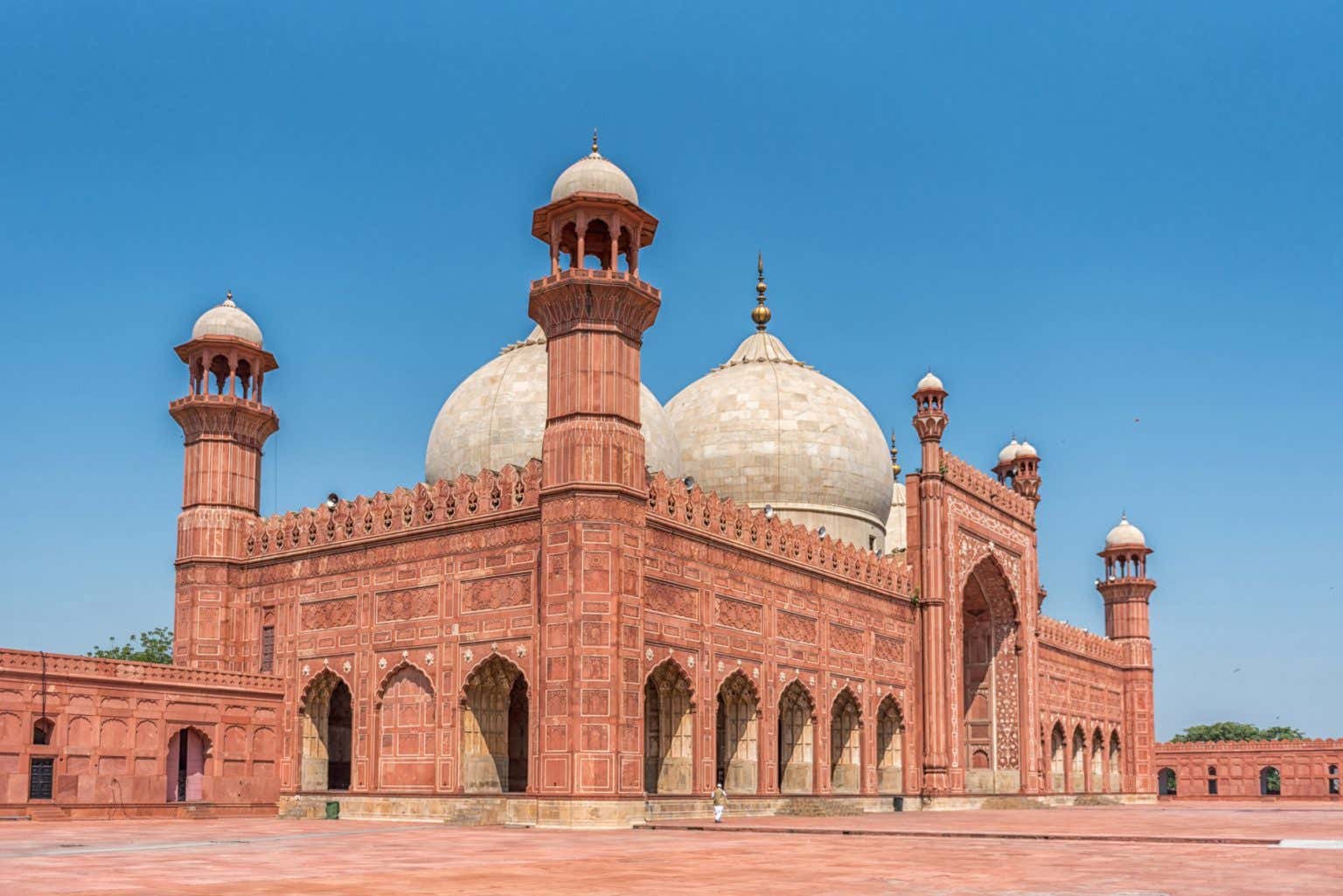 La moschea Badshashi in Pakistan con le mura di colore rosso che la contraddistinguono e il contrasto delle grandi cupole bianche.