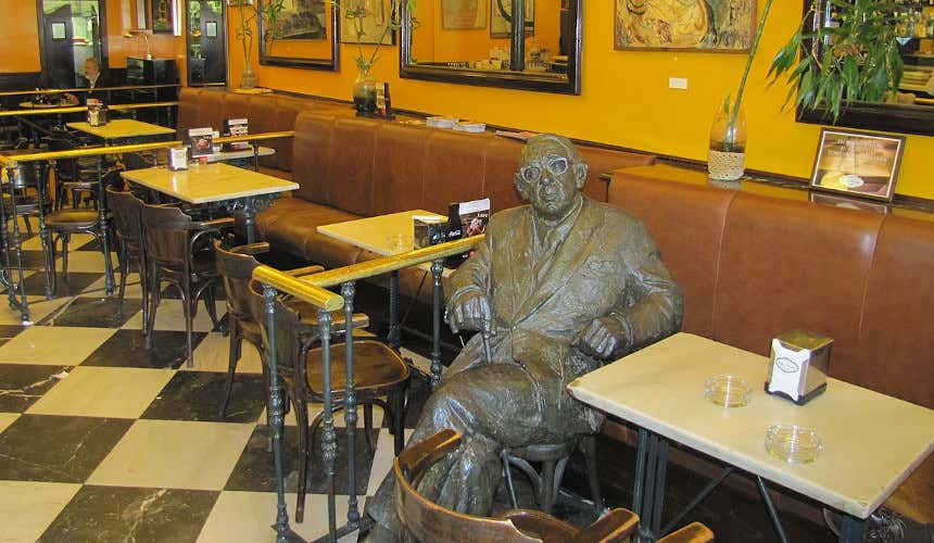 Una statua dello scrittore spagnolo Gonzalo Torrente Ballester seduto al Caffè Novelty di Salamanca, vicino a dei tavolini