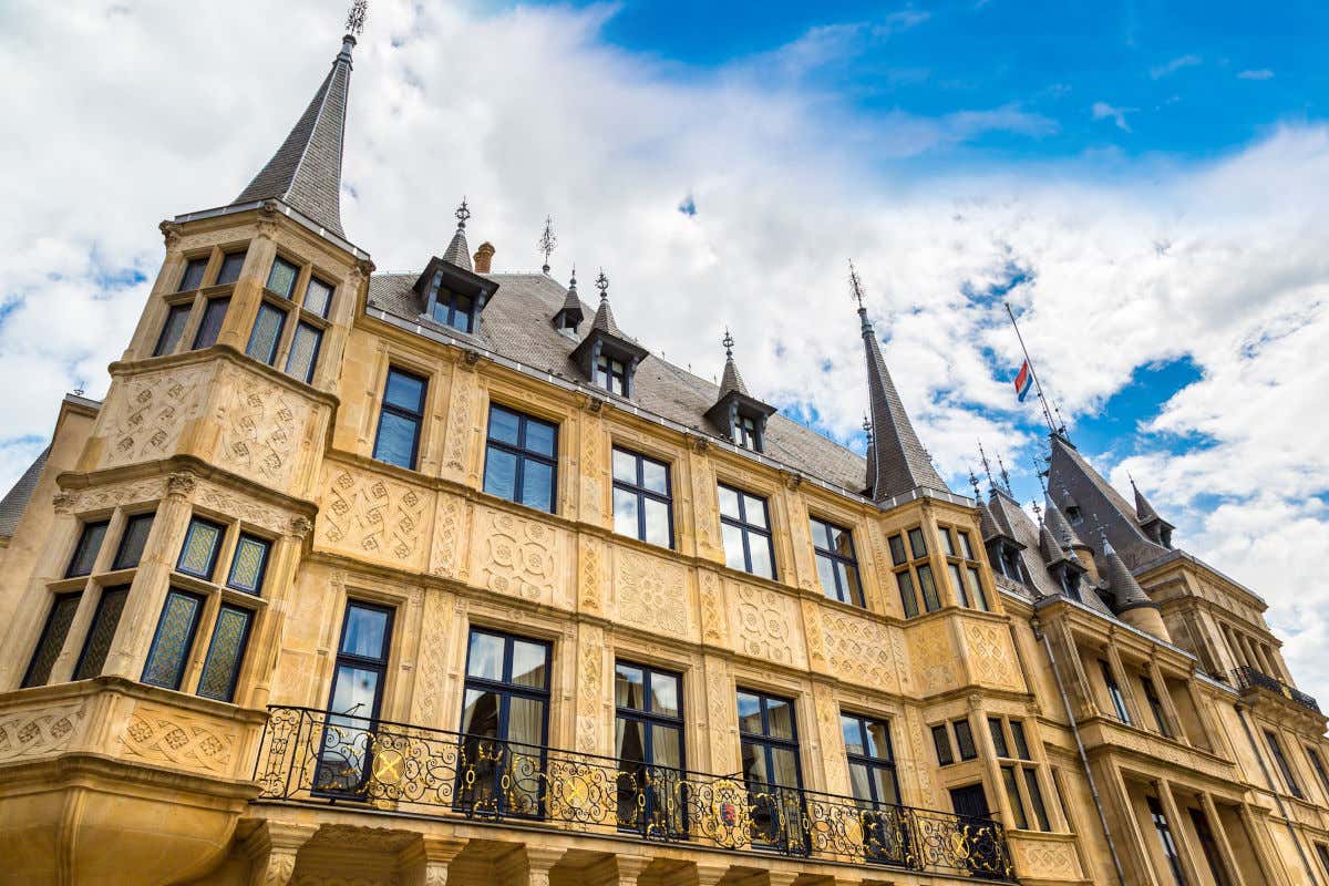 The yellow facade of the Grand Ducal Palace with detailed carvings and towers on a partly cloudy day