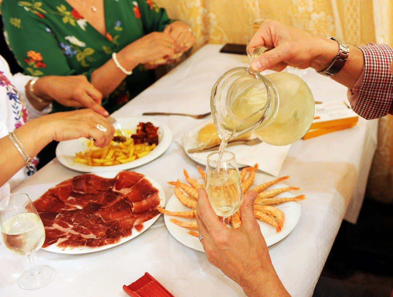 Une personne se servant un rebujito avec diverses assiettes de tapas en fond