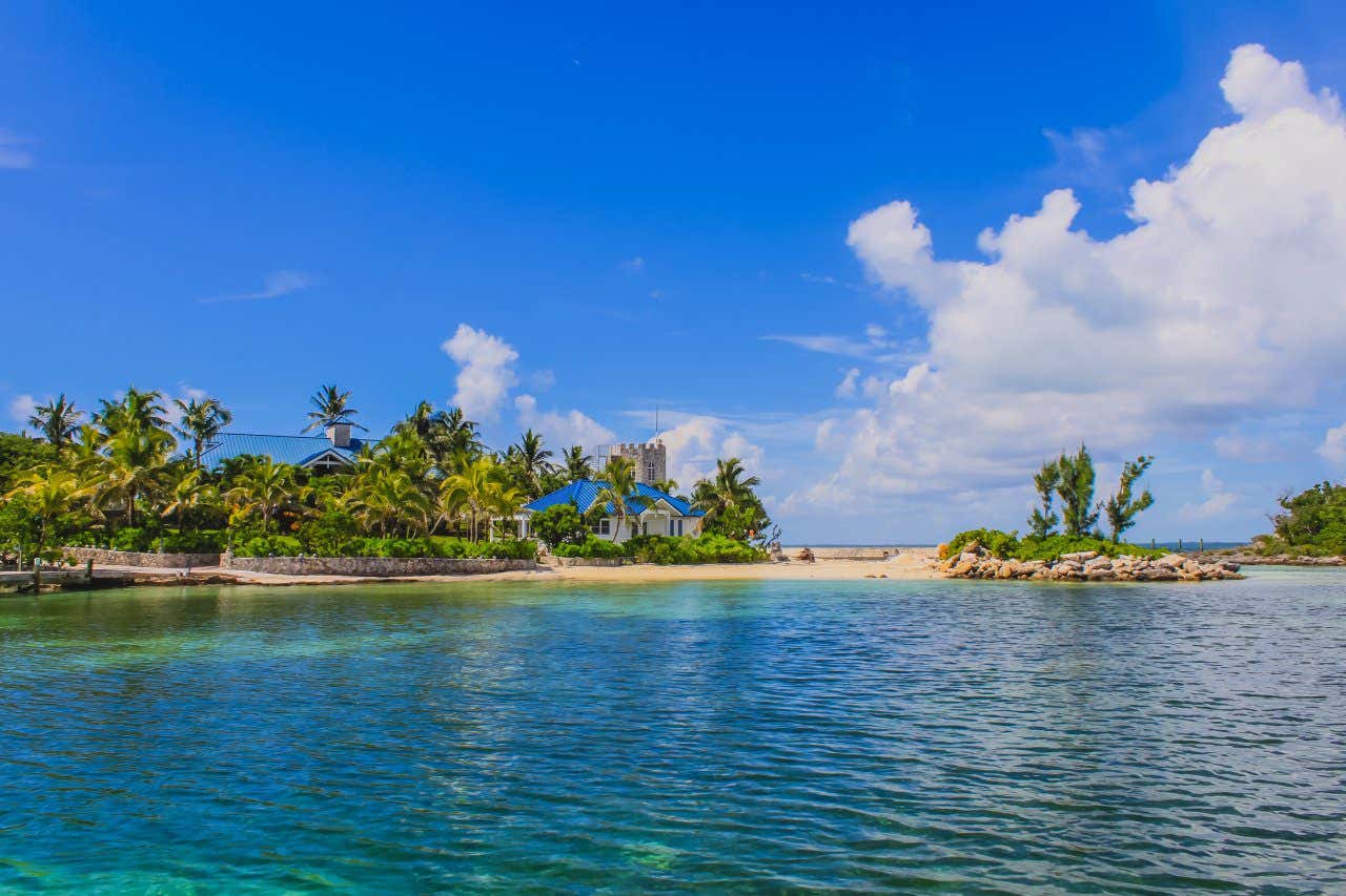 A small bay with turquoise sea water, sandy beach and small white houses with blue roofs on a sunny day