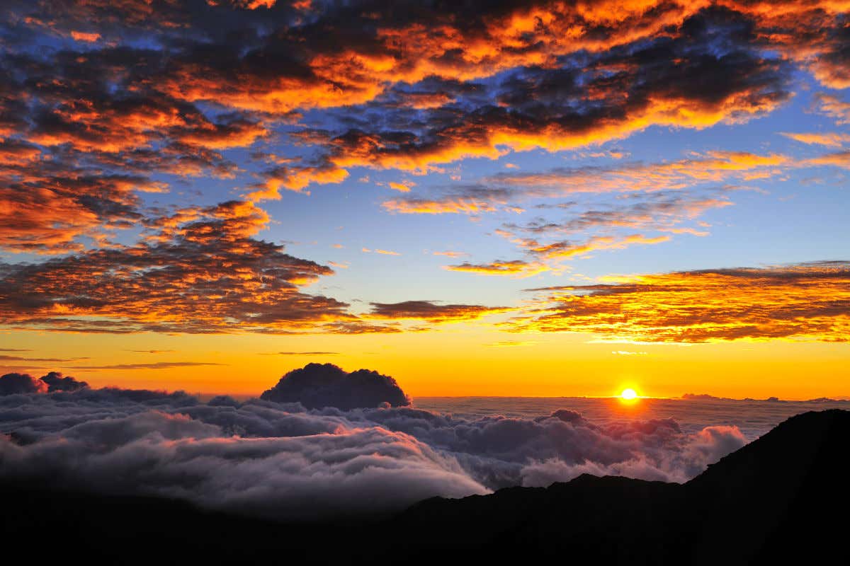 Amanecer desde lo alto del Parque Nacional de Haleakala con el típico mar de nubes y el sol en el horizonte.