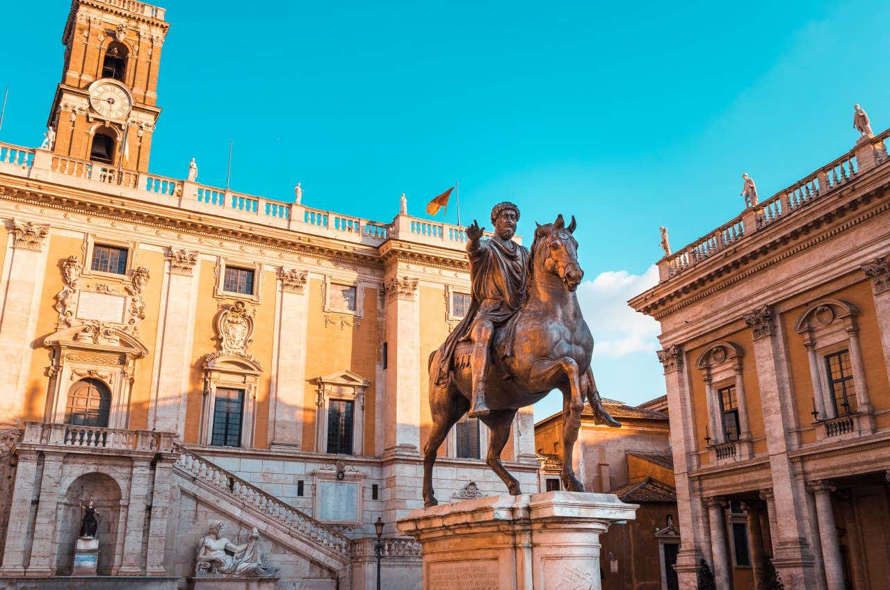 A metal statue of a man riding a horse outside a yellow museum building