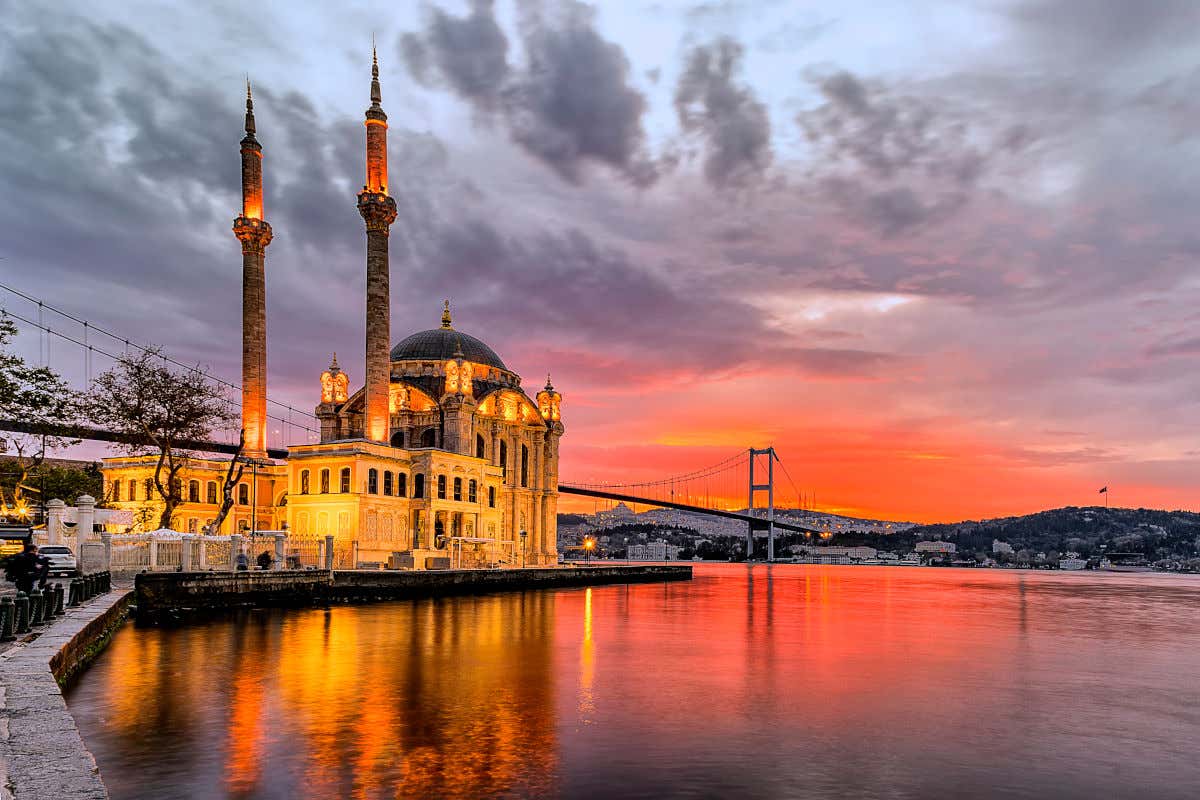 Panorámica de la mezquita de Ortaköy junto al Bósforo y ante un bello amanecer de colores rojizos en Estambul.