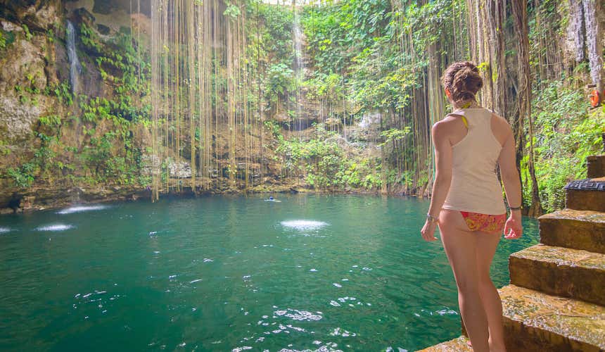 Uma mulher contemplando a paisagem verde do cenote Ik Kil 