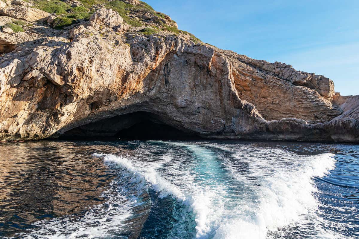 Cuevas marinas de la isla de Cabrera vistas desde un barco que, aunque no se aprecia en la imagen, se deduce por el movimiento y la fuerza del agua de la fotografía.