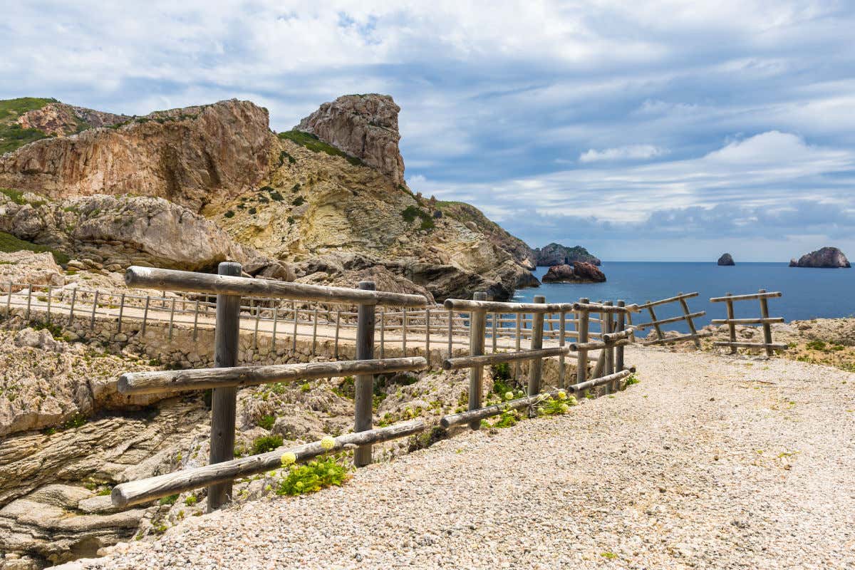 Senderos marcados con vallas de madera del Recorriendo los senderos del Parque Nacional Marítimo-Terrestre de Cabrera. Se pueden divisar pequeños islotes en el mar en calma ante un día nuboso pero con bastante claridad lumínica.