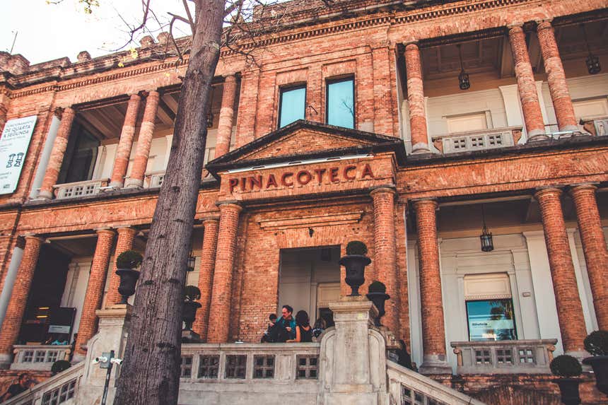 Façade de la Pinacothèque de São Paulo avec des briques et des touristes devant la porte