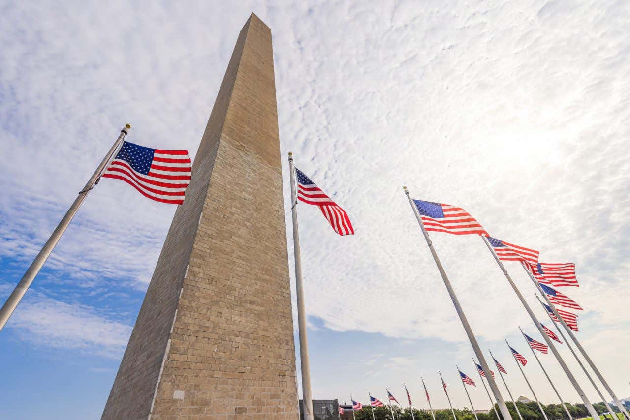 O imponente Monumento de Washington rodeado de bandeiras dos Estados Unidos
