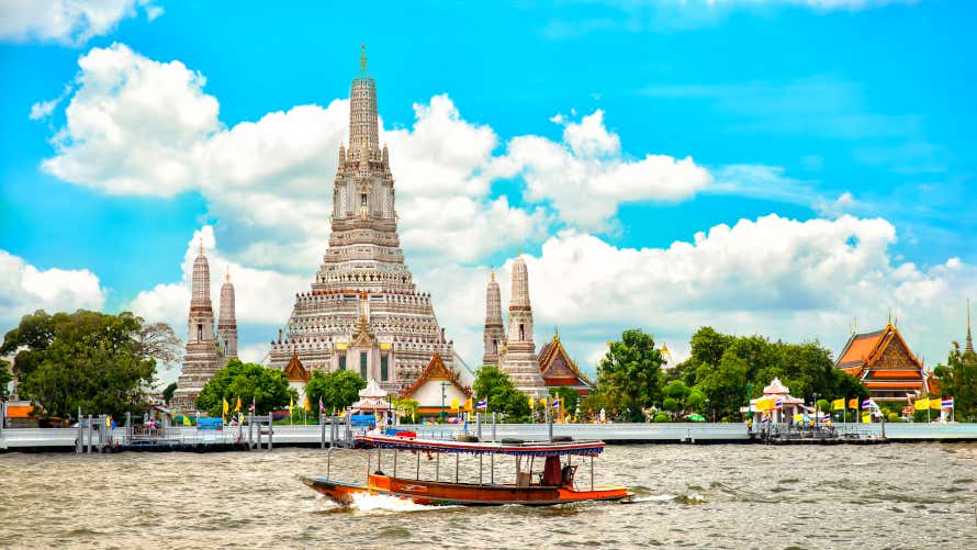 Templo de Wat Arun e o rio Chao Phraya com um pequeno barco cruzando