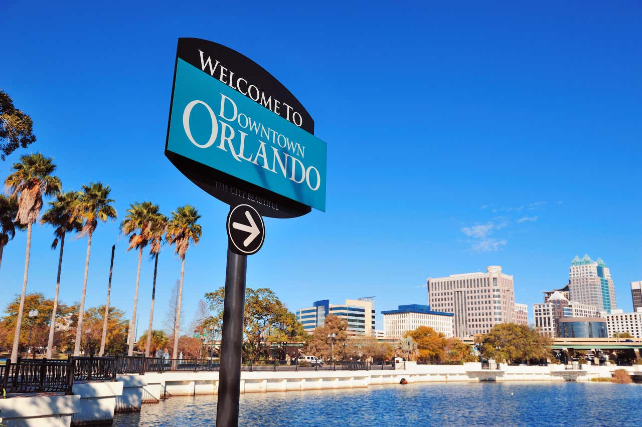 Panneau de l'entrée au quartier du Downtown d'Orlando en Floride avec en fond des palmiers et des bâtiments sous un ciel dégagé