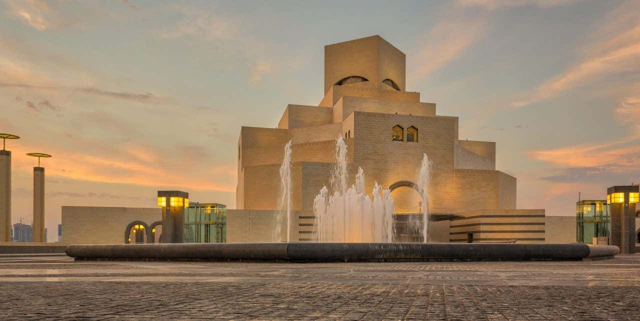 Entardecer sobre o Museu de Arte Islâmica de Doha com uma fonte diante do edifício