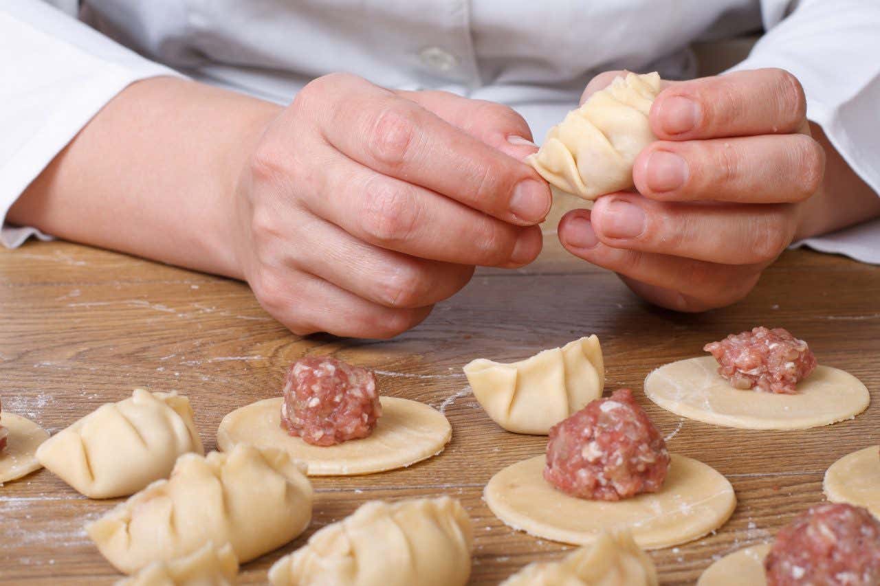 Un cuisinier faisant des jiǎozi avec de la pâte et de la viande dans un atelier de cuisine à Tokyo