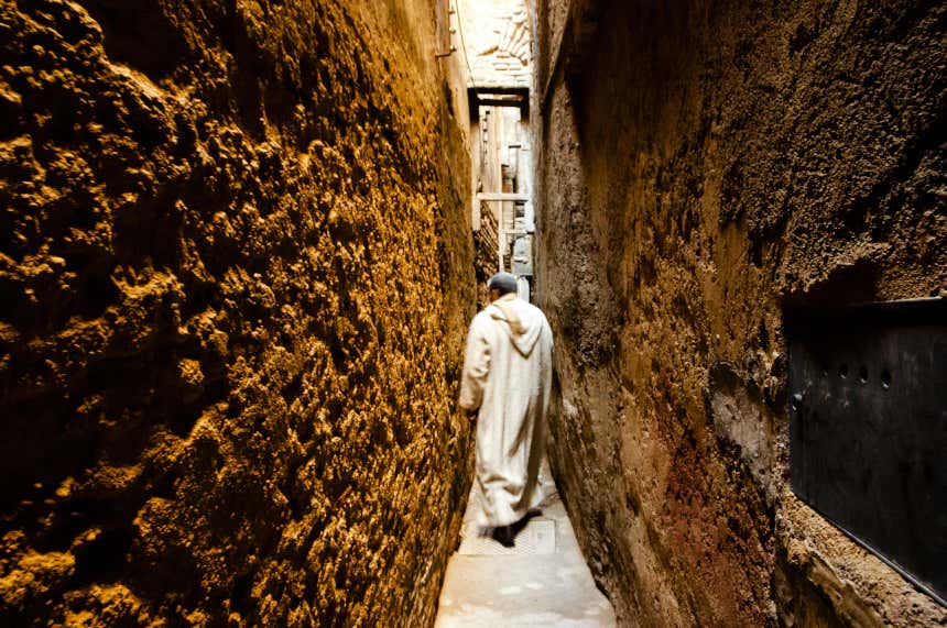 Homem muçulmano caminhando por uma rua estreita da Medina de Fez